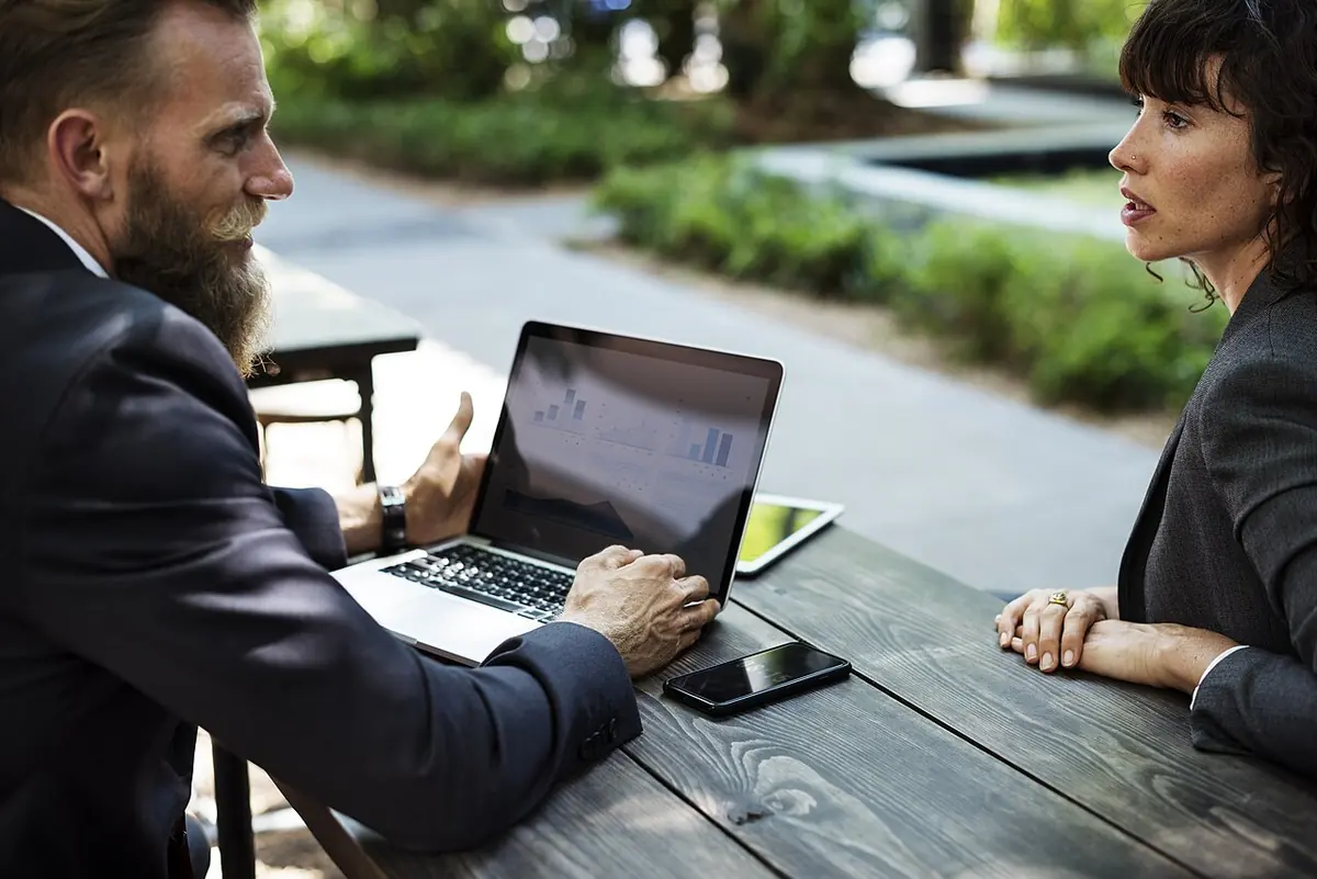 Business owners discussing strategy and technology over a laptop